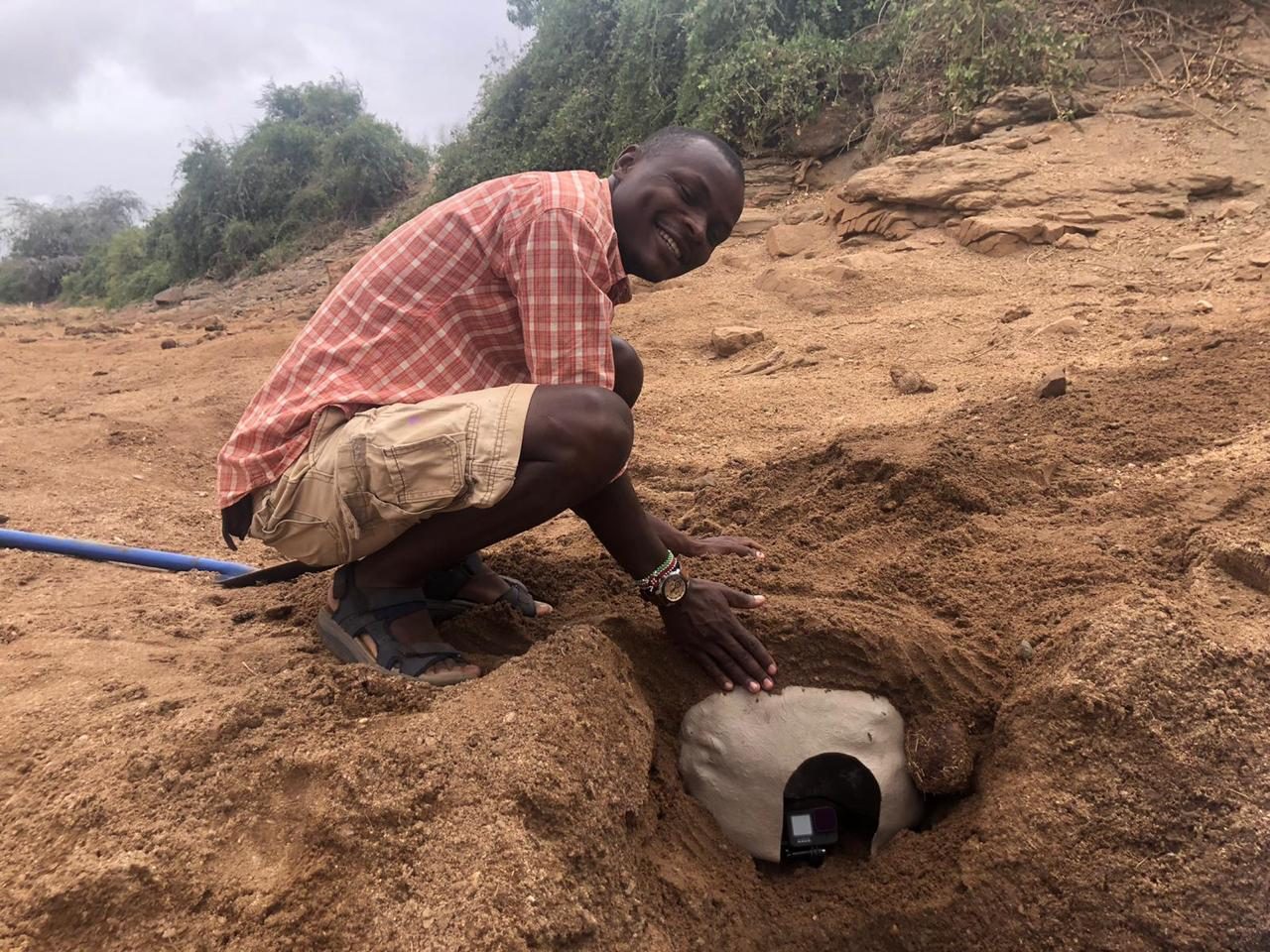 Wickliffe Odera burying a GoPro in a dry riverbed to film elephants drinking from inside the water hole
