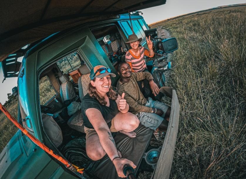 Wickliffe Odera with a film crew in the cab of a tracking vehicle at sunset, Maasai Mara